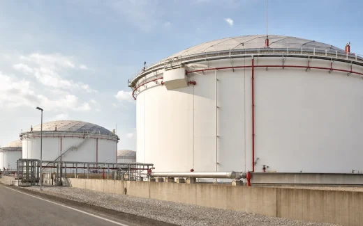 Above-ground steel storage tanks in a contained tank farm with foam piping, cooling-water headers, access routes, and fire-protection infrastructure