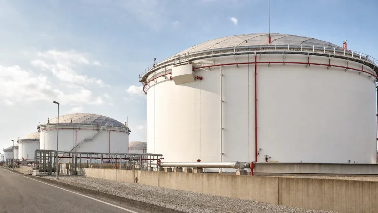 Above-ground steel storage tanks in a contained tank farm with foam piping, cooling-water headers, access routes, and fire-protection infrastructure