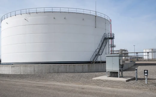 Above-ground steel storage tank on a concrete ringwall with cathodic protection test stations and foundation interface visible at an industrial tank terminal